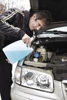 Male driver fills antifreeze liquid in washer window